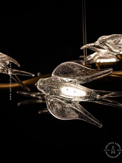 This horizontal chandelier features a flock of glass birds perched on a branch, as if in mid-flight. It's a perfect statement piece for suspension over a long dining table or in a living room, adding a dynamic and natural element.