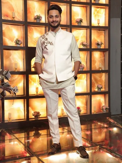 Clean, crisp, and effortlessly elegant. This custom-made Indowestern set features a white bandhgala jacket with delicate floral embroidery on the shoulder, paired with a contrasting inner kurta and tailored trousers.