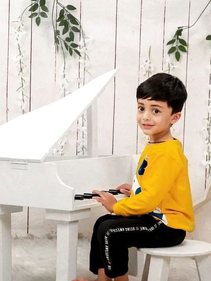 Another take on our popular little musician theme. This young boy looks like a professional pianist, seated at our miniature white piano in a clean, bright studio setting.