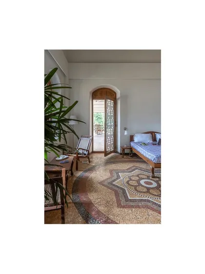 Another view of the restored bedroom, highlighting the stunning star-patterned mosaic floor. We designed the new solid wood door and furniture to complement the tones and textures of this original feature.