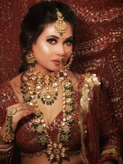 A stunning bridal portrait featuring a heavy, layered Kundan and emerald set. The rich colors and intricate details are breathtaking.
