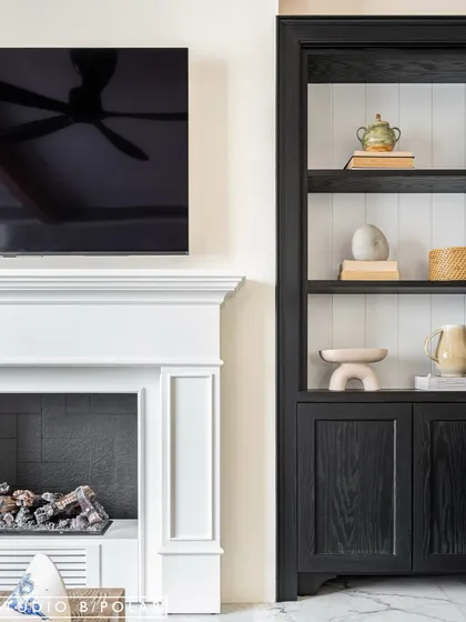 A close-up of the fireplace and display unit shows the clean lines and classic details that define this space. The design is a layered blend of traditional, mid-century, and contemporary styles.