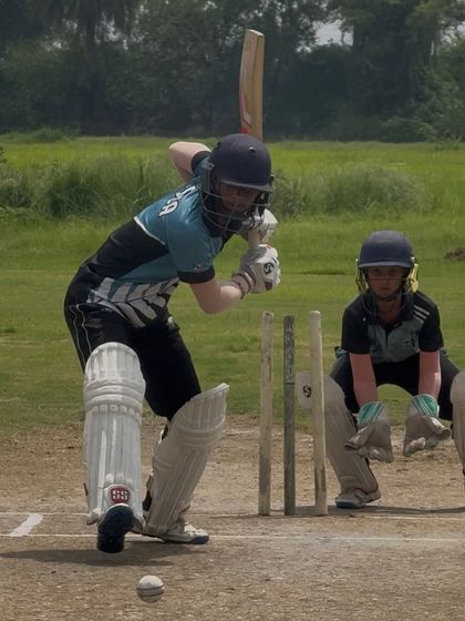 A young batter playing a defensive shot in a practice match, with the wicketkeeper watching closely. Match simulation is a key part of our training.