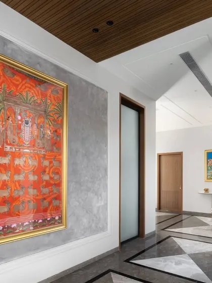 Another view of the art-filled corridor, showing the beautiful contrast between the textured grey wall, the vibrant traditional art, and the sleek, modern flooring.
