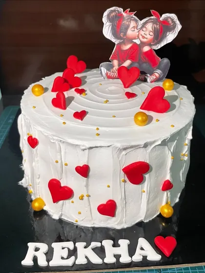 This charming cake is decorated with a cascade of red hearts and a cute illustration of two girls. It’s a simple, heartwarming design perfect for celebrating a close friendship or sisterly bond.