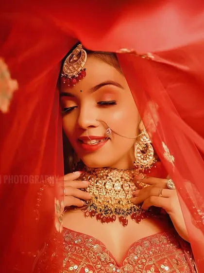 A beautiful shot of the bride smiling with her eyes closed, capturing a moment of pure bliss. The red veil adds a layer of tradition and romance.