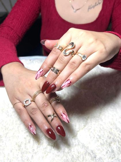 A stiletto set with a deep red base and a pink marble effect on the accent nails. This is a great way to combine a classic color with a trendy pattern.
