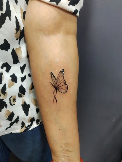 A delicate butterfly tattoo on the arm. The fine lines and simple shading make it look light and graceful.