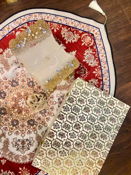 A beautiful Ramadan gift set featuring a dome-shaped prayer mat with an intricate red and white design. The set includes a custom Quran holder and a crystal tasbeeh, making it a perfect gift for the holy month.