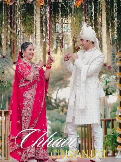 A playful and happy moment during the wedding ceremony. The couple, dressed in beautiful red and white traditional attire, shares a fun, candid interaction under the floral mandap.