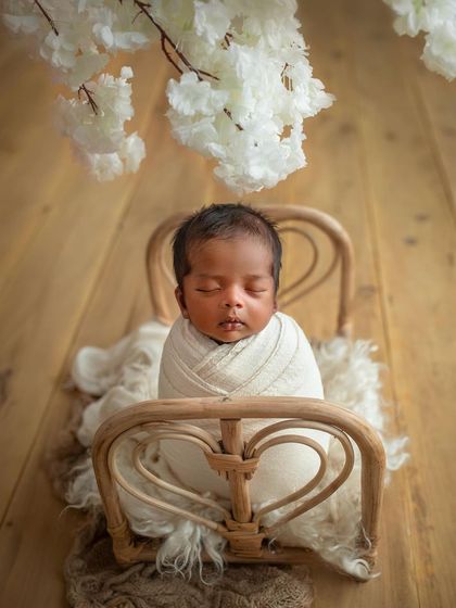 A simple and classic setup with the baby wrapped in white on a tiny rattan bed. This timeless look is always a favorite.