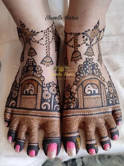 Your mehendi design can extend to beautiful patterns for your feet. This bridal feet design includes charming baby elephant motifs within traditional architectural frames, complete with delicate hanging jhumka details for a royal touch.