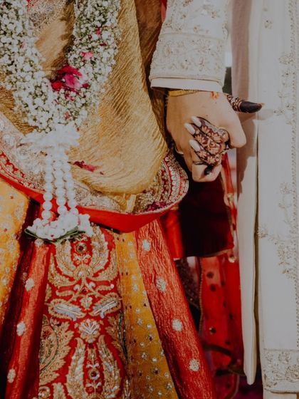 A close-up on the couple's hands during the ceremony, showcasing the bride's intricate henna and the joining of their lives.