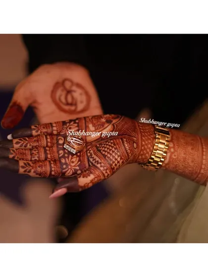 A beautiful photo showing both the bride's and groom's henna stains. The bride's intricate design and the groom's simple symbol both have a lovely, rich color.