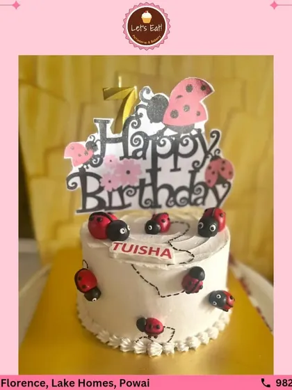 A sweet and simple ladybug-themed birthday cake. The white frosted cake is adorned with cute, handcrafted fondant ladybugs, perfect for a charming and whimsical celebration.
