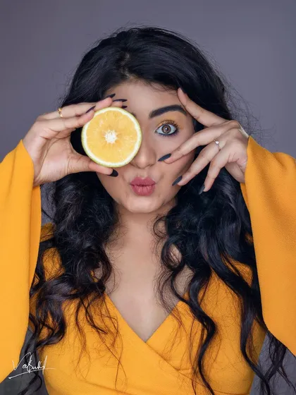 A playful and creative studio portrait. Using a slice of orange as a prop adds a fun, quirky element, while the model's expression brings a burst of personality to the shot.
