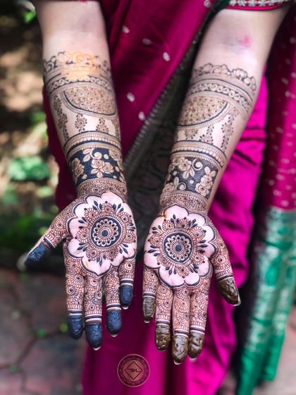 A beautiful bridal design featuring large mandala flowers on the palms. The forearms have a mix of modern and traditional elements, including paisleys and floral bands.