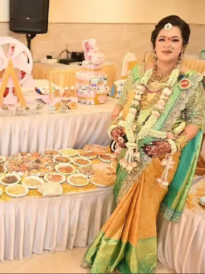 A beautiful mom-to-be posing proudly next to the extensive food and dessert table we created for her baby shower.