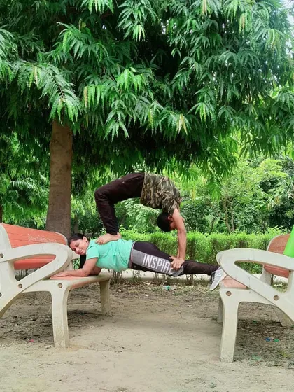 Using park benches to create a unique partner pose. This combines a strong plank hold with a deep backbend in Chakrasana, showing how you can use your environment to enhance your practice.