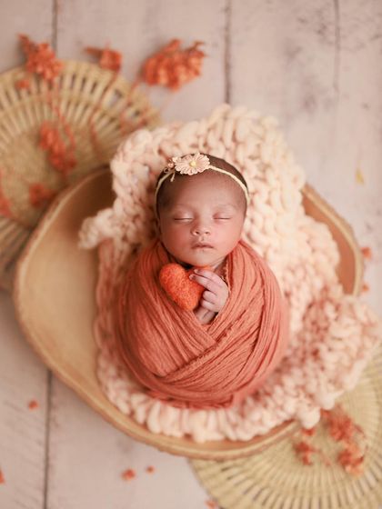 Isn't she adorable? The warm, peachy-orange tones of the wrap and props create a lovely, inviting feel for this heart-warming portrait.