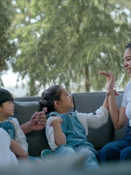 A family of four interacts and plays together on an outdoor sofa, a perfect candid moment.