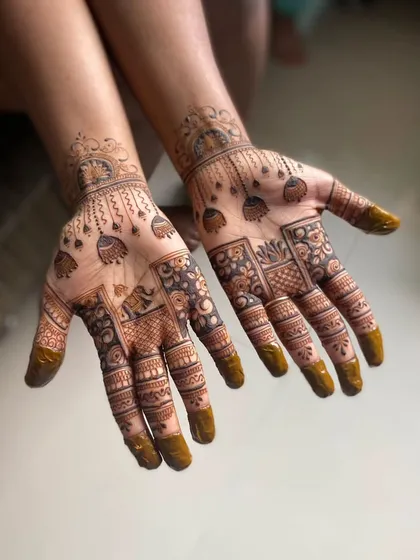 A design filled with festive elements, including hanging jhumkas and small elephant motifs. The mix of bold shapes and fine lines gives this Karwa Chauth mehendi a rich and celebratory feel.