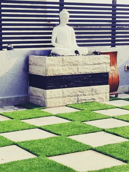 A Buddha statue on a stone podium serves as a peaceful focal point on this terrace with checkerboard-patterned flooring.