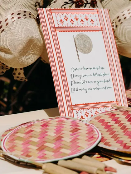 Thoughtful details for guests. These traditional hand fans are accompanied by a sweet note, offering guests a 'breeze from a distant place' and a piece of the couple's story to take home.