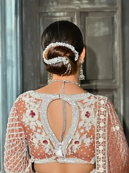 A sleek and sophisticated bridal bun, accented with an elegant pearl hair accessory. This modern updo is perfect for a bride looking for a minimalist yet refined hairstyle for her reception or engagement.
