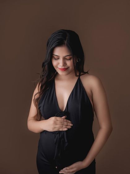 A beautiful solo portrait of a mom-to-be in a black halter dress, looking thoughtfully to the side.
