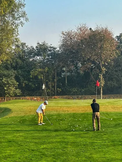 Two golfers work on their short game from different lies on our practice green.