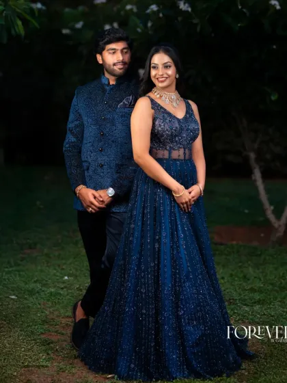 This is a great example of a coordinated look for a modern reception. The groom's custom dark blue bandhgala jacket features a subtle, all-over texture that perfectly matches the bride's dazzling evening gown.