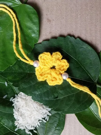 A simple and elegant yellow flower rakhi with pearl details.