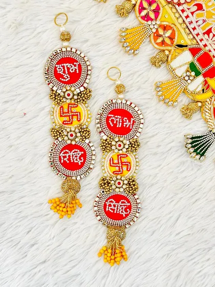 A detailed look at the Shubh, Labh, Riddhi, and Siddhi hangings. Each piece is crafted with red and yellow beadwork to bring blessings and good fortune.