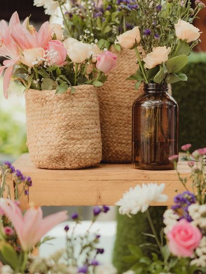 A detail shot of the floral decor, featuring soft pink roses and other blooms in rustic jute-wrapped vases.