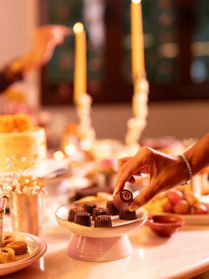A hand selecting one of our Lonavala Chocolate Bonbons from a beautifully arranged dessert platter.