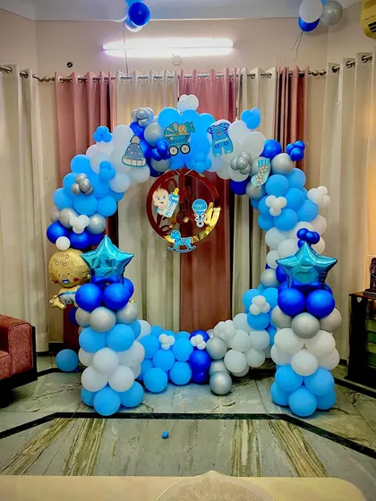 Another view of a home-based celebration for a baby boy. The balloon ring is decorated with cute baby-themed cutouts and foil balloons, transforming the living room into a party zone.