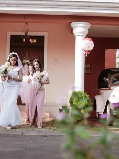 The bride and her bridesmaids walking towards the vintage wedding car. A classic, elegant moment from a Goa wedding.