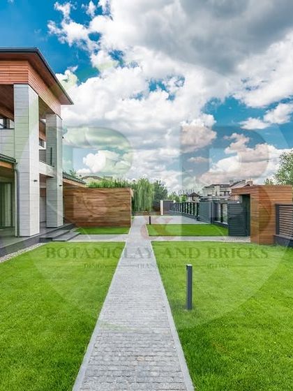 A modern home deserves a modern landscape. This design features a clean, expansive lawn with a simple paved walkway, complemented by a minimalist fence, creating a sleek and uncluttered look that enhances the architecture.