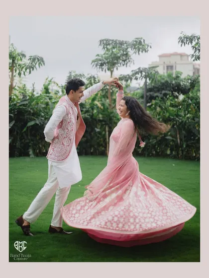 A beautiful, dynamic shot of the groom twirling his bride on a lush green lawn. The movement of her lehenga and their joyful expressions make this a perfect Roka portrait.
