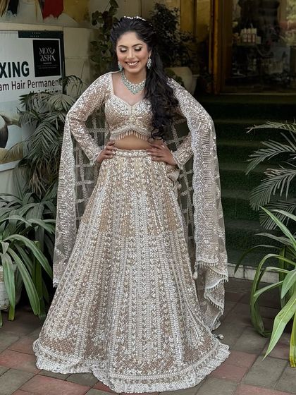 A full-length shot showing off her gorgeous sequined lehenga and the flowing, curly hairstyle adorned with a pearl hair accessory.