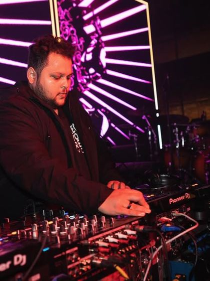 A focused shot of me mixing during a back-to-back set, with the stage lights creating a dynamic backdrop.