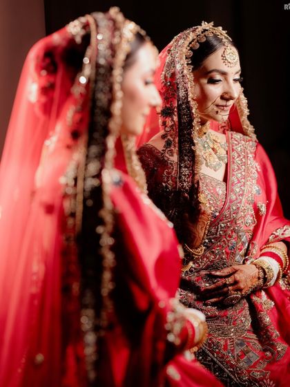 A beautiful and intimate portrait of the bride looking at her reflection in a mirror, a quiet moment of contemplation on her wedding day.