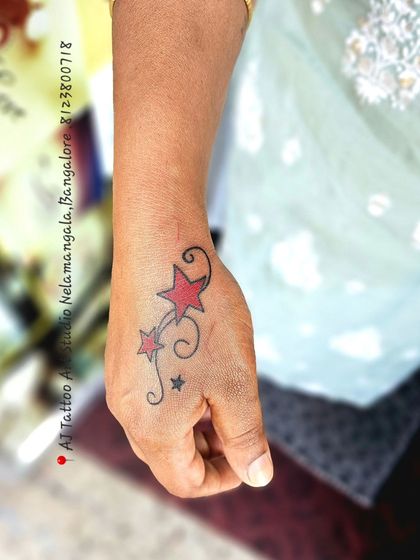 A small design of red stars with black swirls on the hand.