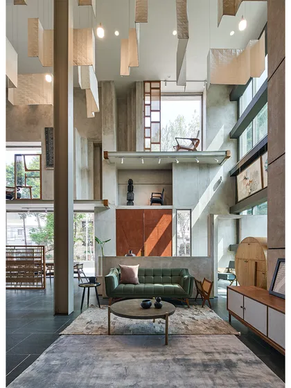 A curated furniture setting within the Magari store. The raw concrete walls and tall windows provide a neutral yet dramatic backdrop for the products.