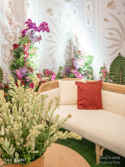 A close-up of the entrance lounge seating, showing the comfortable sofa and the beautiful contrast between the red patterned cushion and the fresh white floral arrangement.