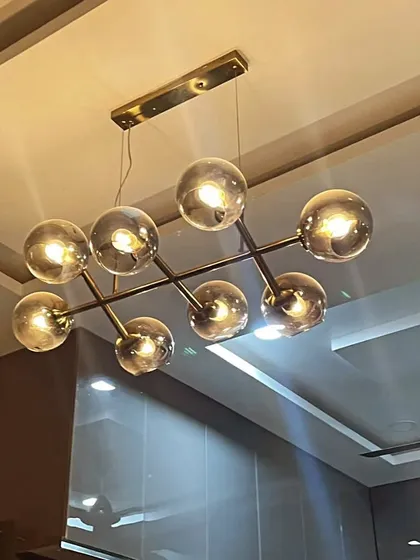 Illuminate your dining area or living room with this stunning 8-light chandelier. The design features smoked glass globes arranged on an antique brass frame, providing a modern yet timeless lighting solution that elevates any space it occupies.