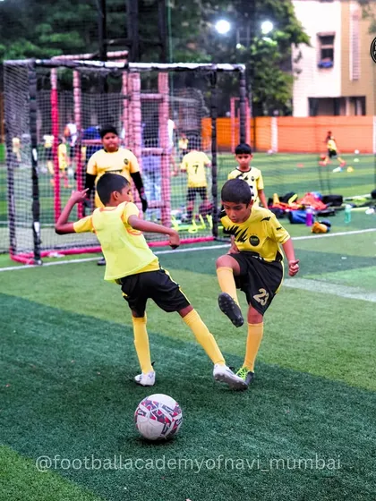A friendly but competitive tackle during a practice game, where players learn to challenge for the ball safely.