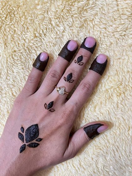 A minimalist design with a single large leaf motif and smaller leaves scattered on the fingers.