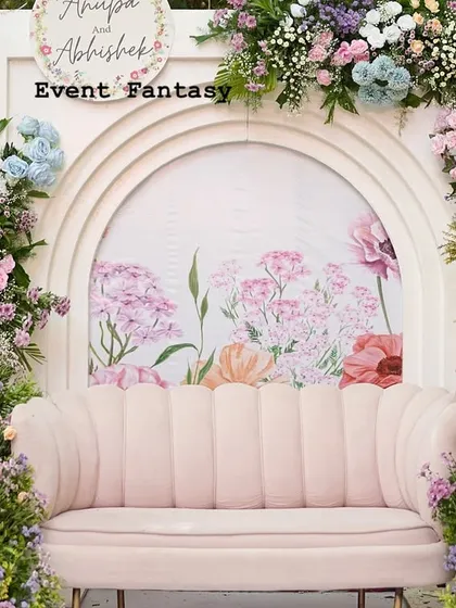 A full view of the pastel floral stage, ready for the celebration. The design features a custom-painted backdrop and asymmetrical floral arrangements on modern white arches, creating a unique and artistic look.